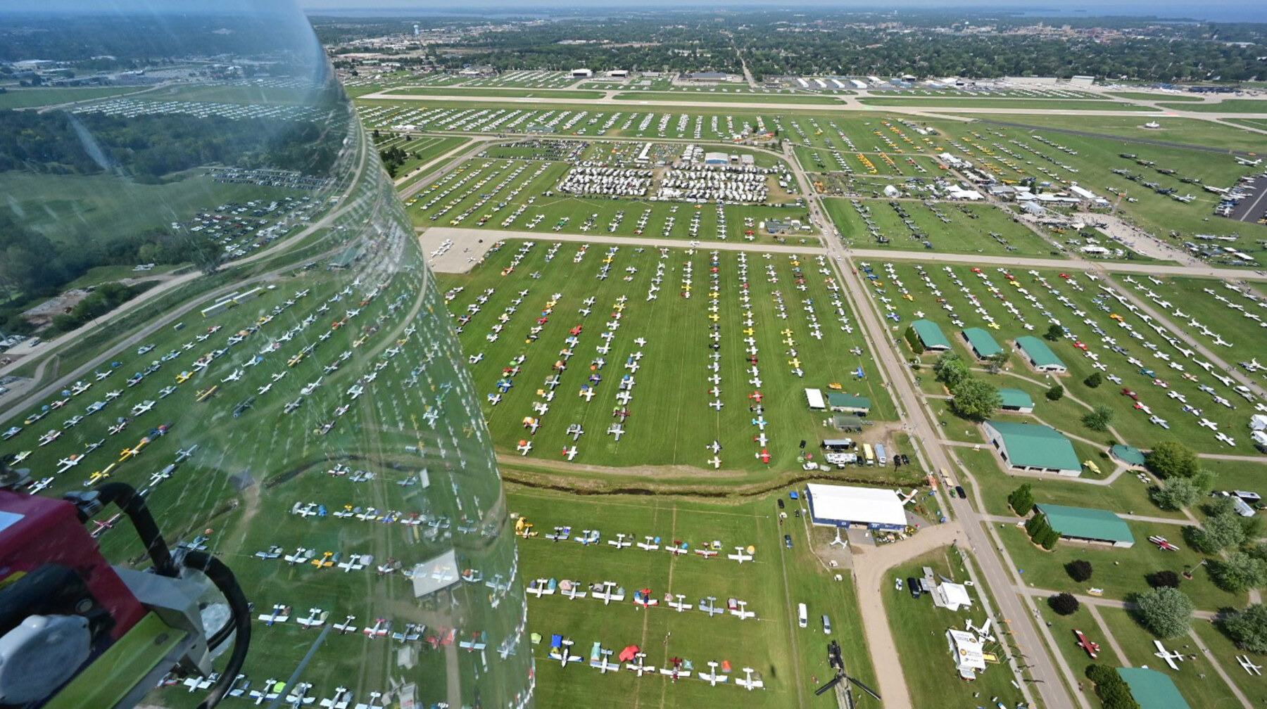 Aircraft parked across a wide grass ramp at Oshkosh.