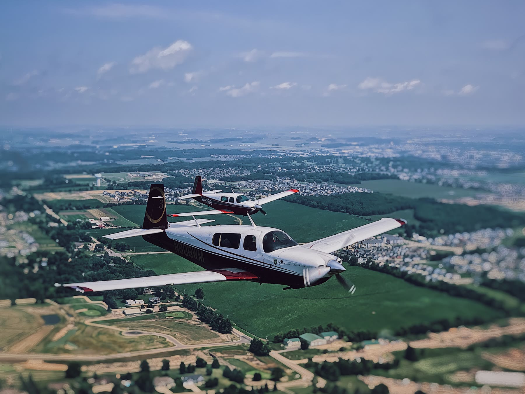 Two Mooneys in formation enroute, tilt-shift treatment