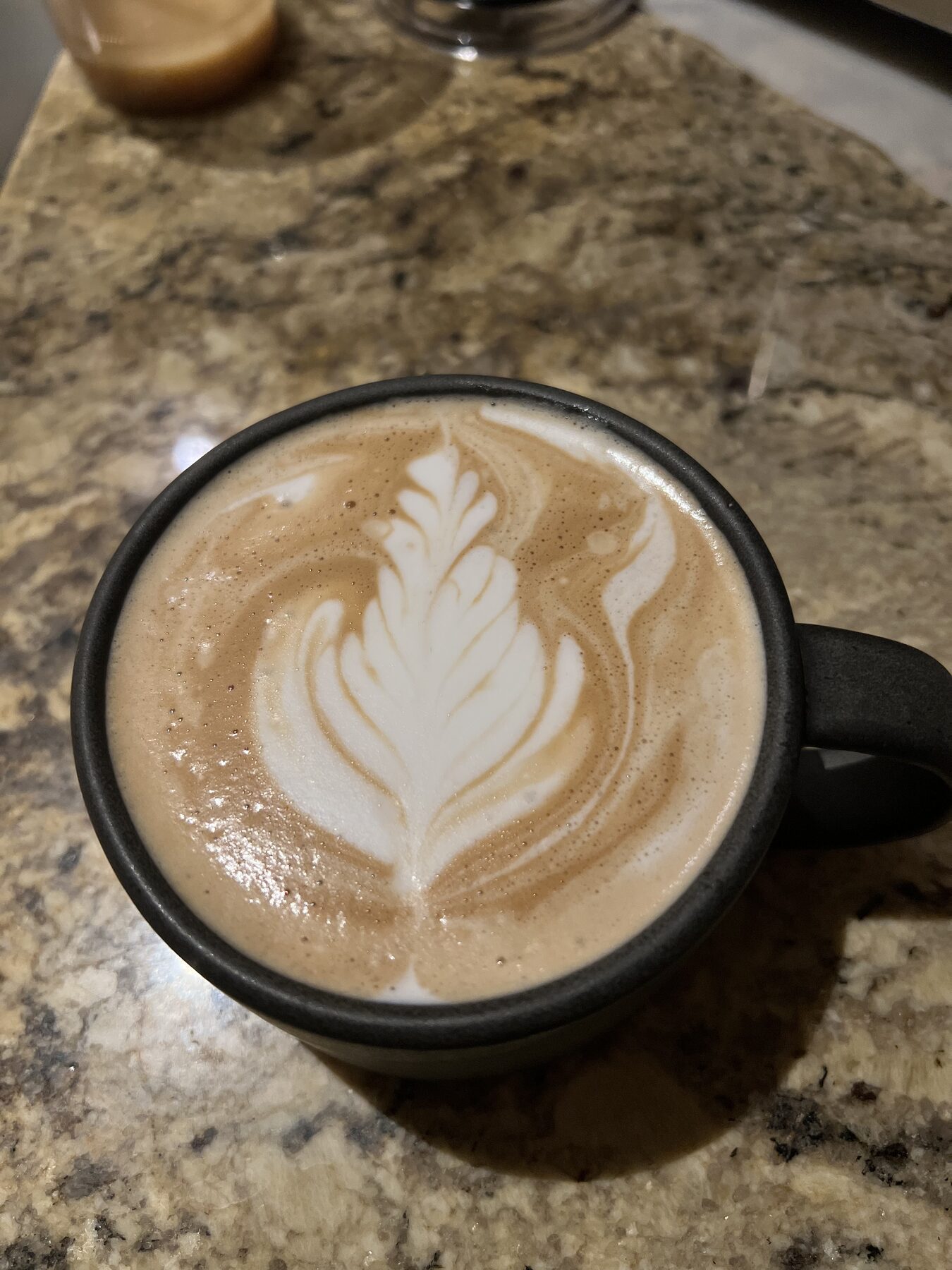 A finished milk drink in a cup, photographed from above, with poured leaf latte art.