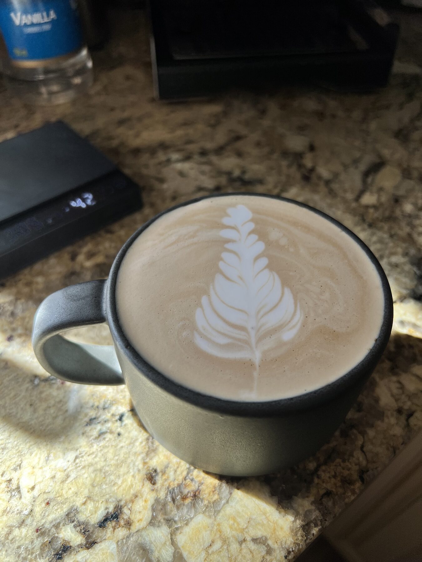 Tulip in a green ceramic mug on speckled granite.