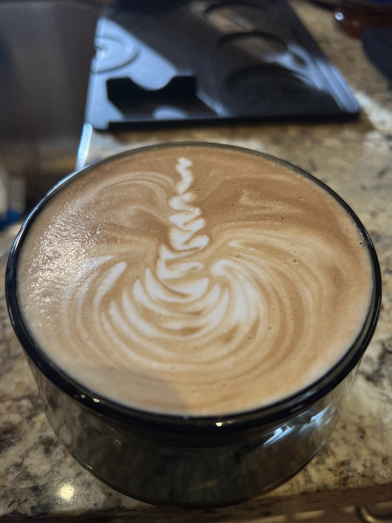 Soft swirl-and-stem tulip, glass cup, dark background.