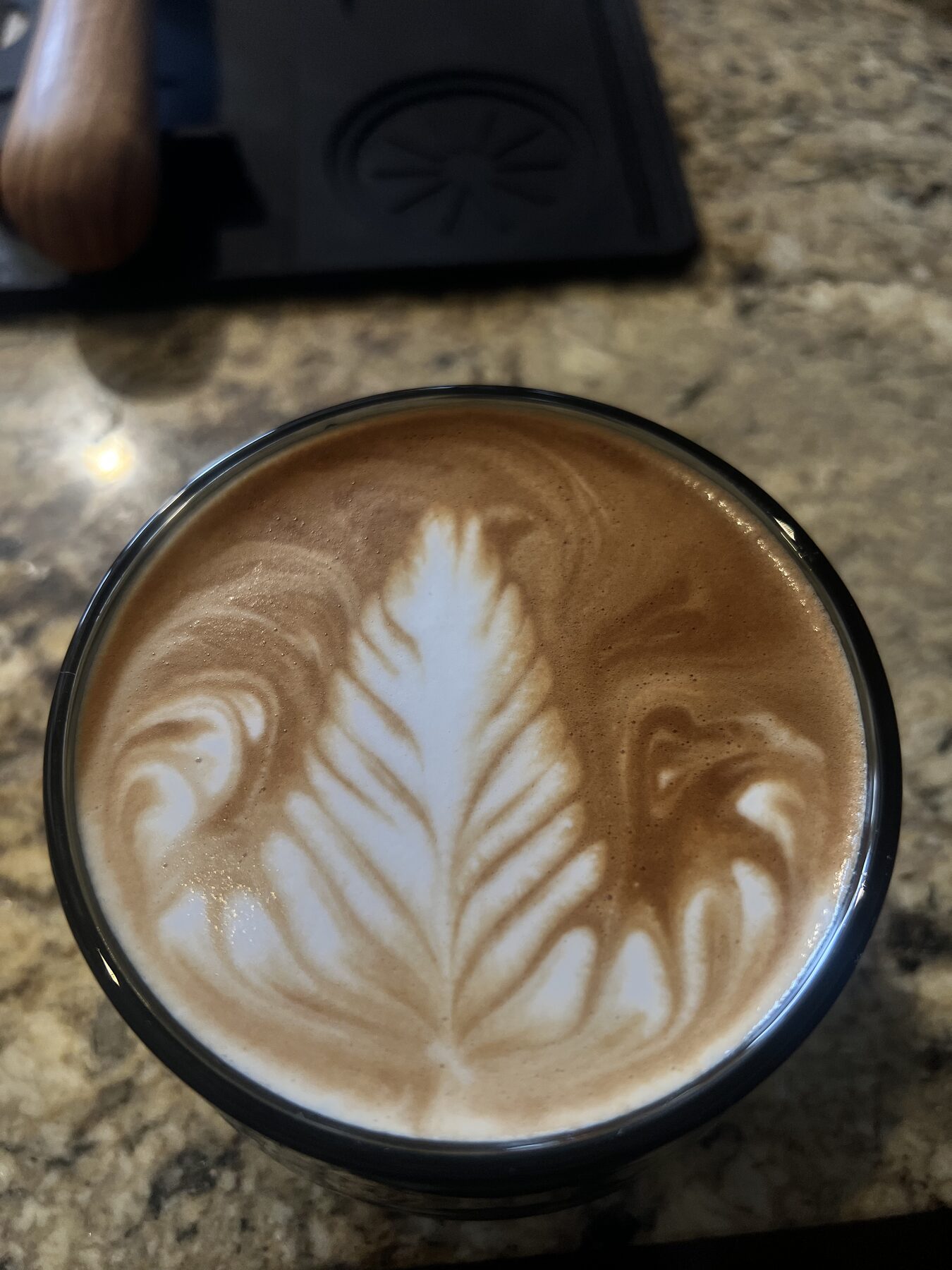 A finished milk drink beside the machine it was pulled on.