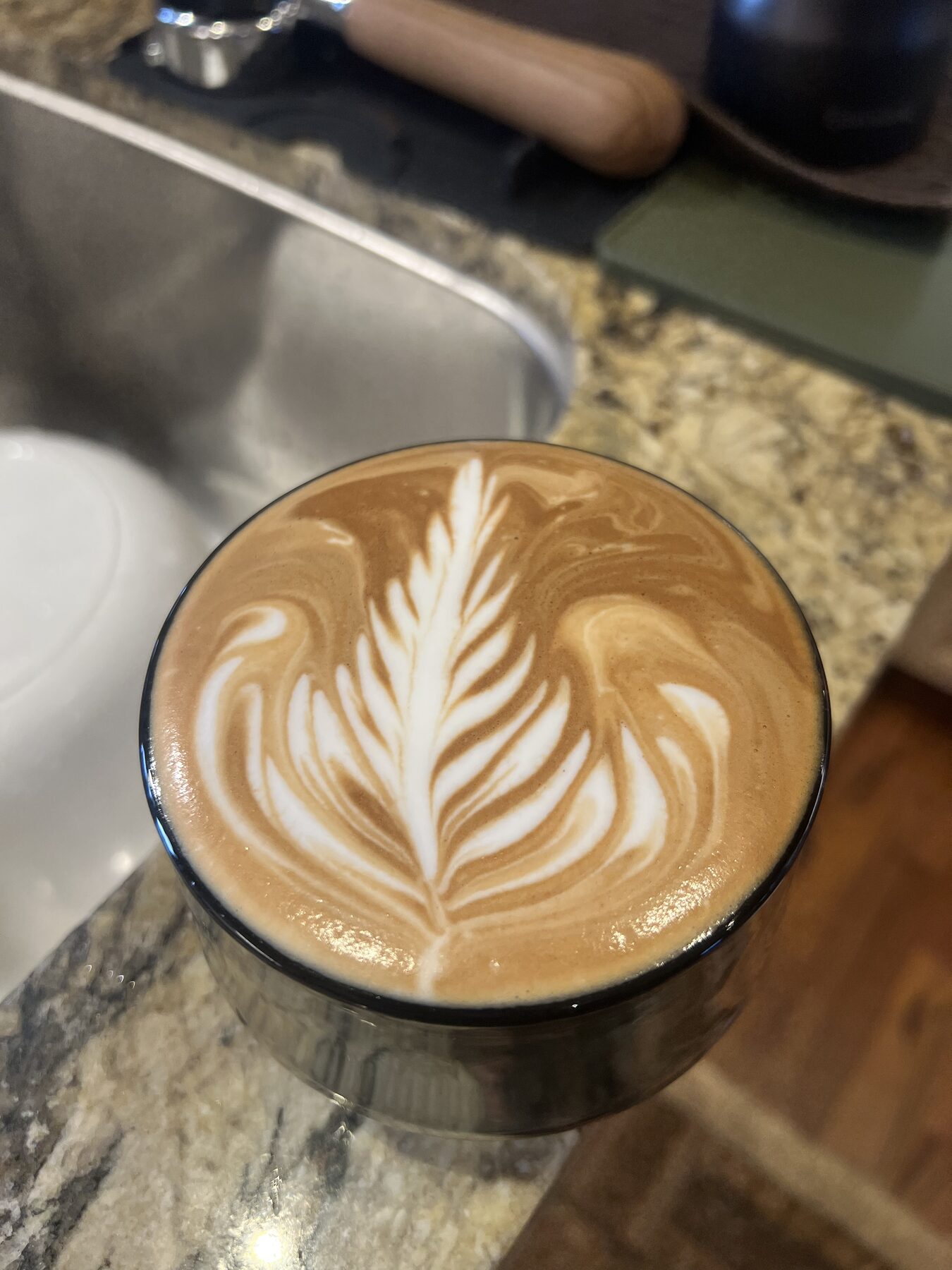 A finished milk drink in a cup, photographed from above, with poured leaf latte art.
