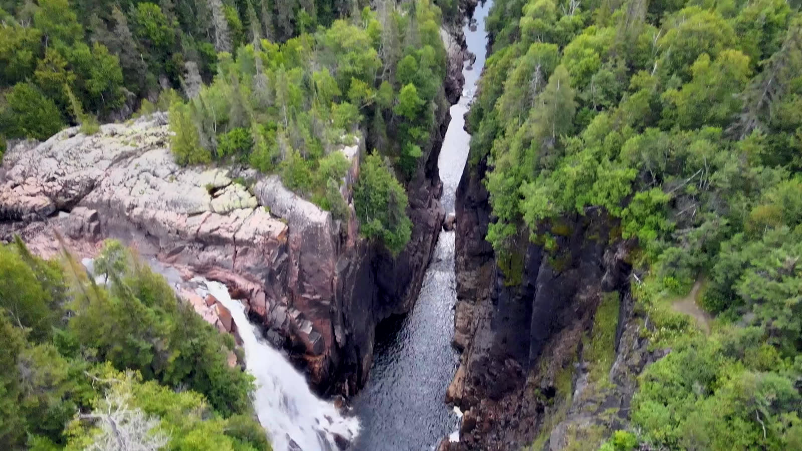 The Aguasabon Gorge from the air, dark water running out between forested rock walls.
